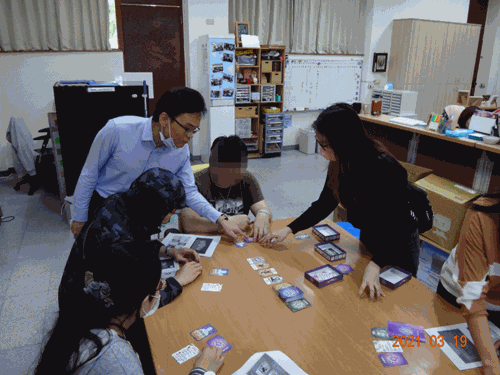 鍾分署(右二)與詹校長(左二)及同仁手持王牌執行官桌遊卡牌留影及邱俊諭執行官(左站立者)在東華大學指導學生玩王牌執行官桌遊